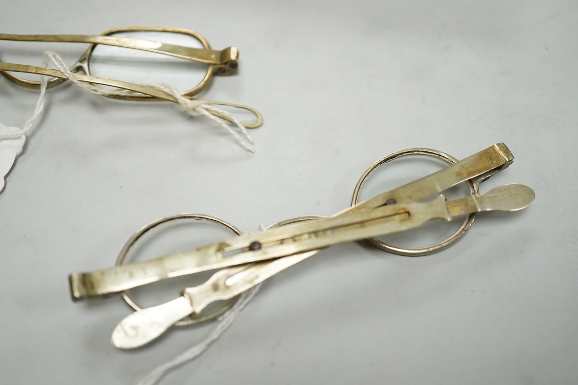 Three pairs of early 19th century base metal slider spectacles, pseudo hallmarks, one also stamped Pebbles, and two pairs of similar temple spectacles, the pair with turn pin sides also stamped pebbles, the pair with obl